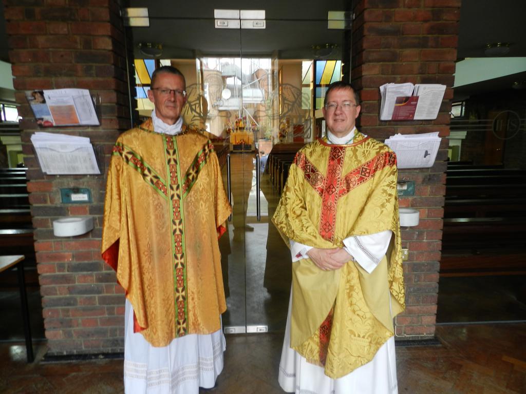 Fr Kevin Jordan and Bishop John Sherrington, standing in front of the glass doors